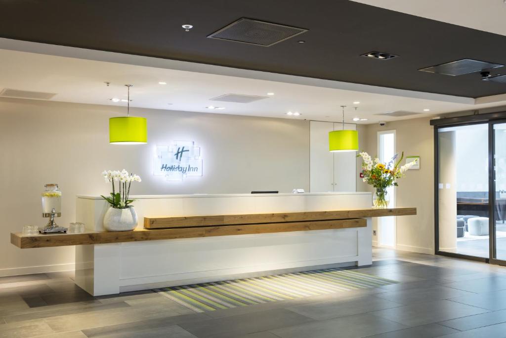 a lobby with a reception desk with yellow lights at Holiday Inn Amsterdam - Arena Towers, an IHG Hotel in Amsterdam