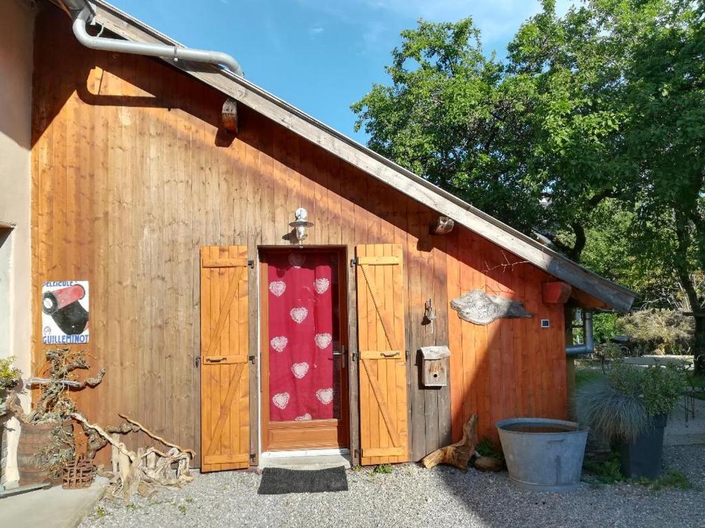 a building with a red door with a red and white curtain at Le Gîte de la Maison Soleil, entre lac et montagne in Alex