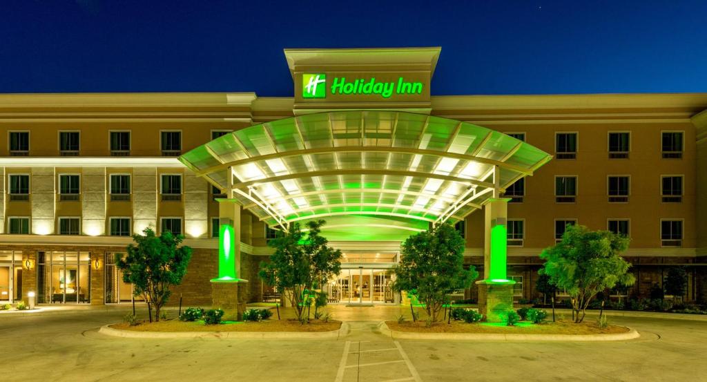 un edificio de hotel con un cartel en la parte delantera en Holiday Inn Austin Airport, an IHG Hotel, en Austin