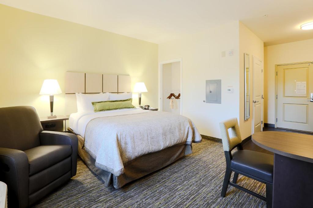 a hotel room with a bed and a desk and a chair at Candlewood Suites Auburn, an IHG Hotel in Auburn
