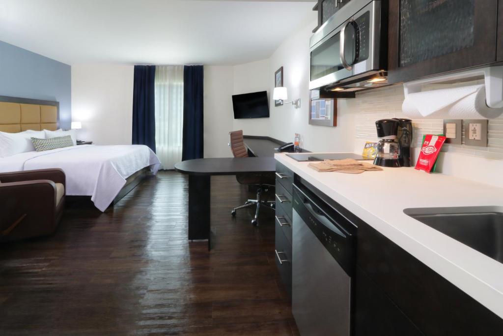 a hotel room with a bed and a kitchen with a sink at Candlewood Suites - Celaya by IHG in Celaya