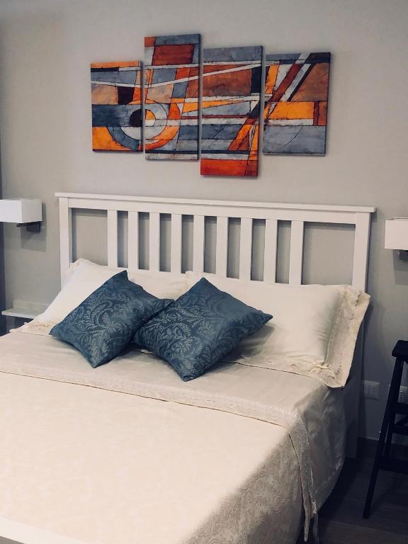 a white bed with three paintings on the wall at Classic Home in Castelbuono