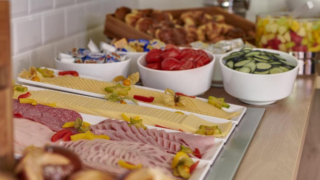 a table topped with different types of meats and vegetables at Holiday Inn Express Cologne Troisdorf, an IHG Hotel in Troisdorf