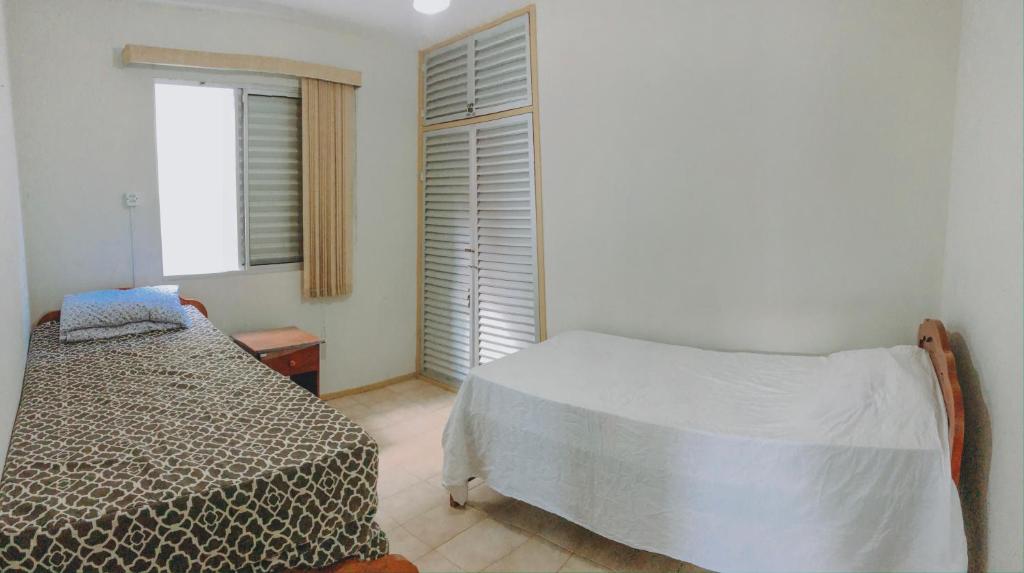een kleine slaapkamer met een bed en een raam bij Apartamento em Ubatuba 50m do mar Praia Grande in Ubatuba