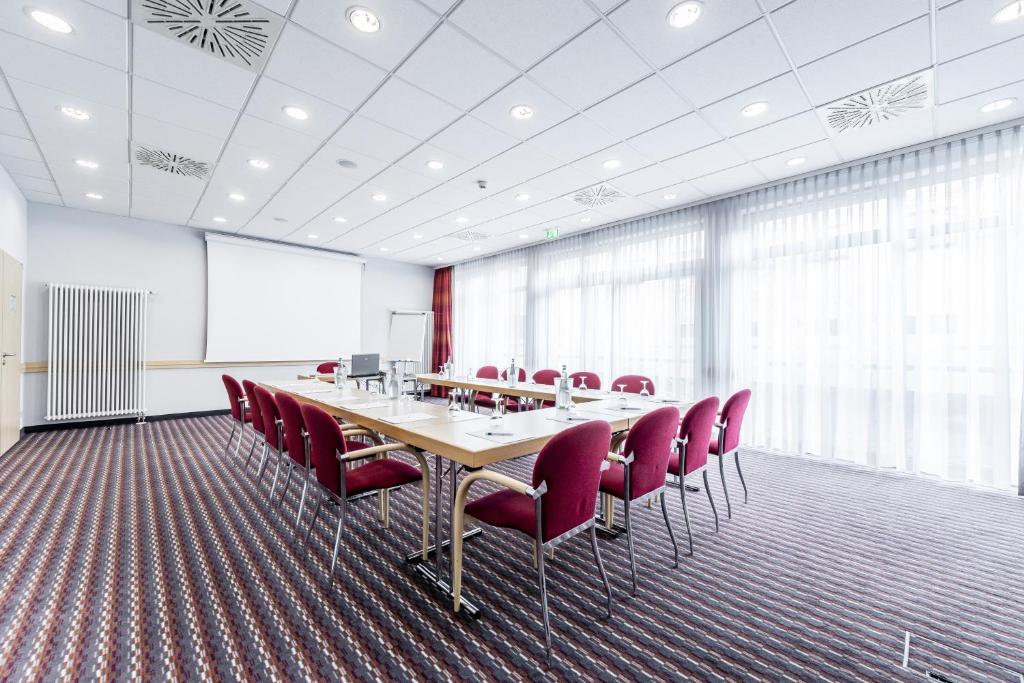 einen Konferenzraum mit einem langen Tisch und roten Stühlen in der Unterkunft Holiday Inn Express Berlin City Centre, an IHG Hotel in Berlin