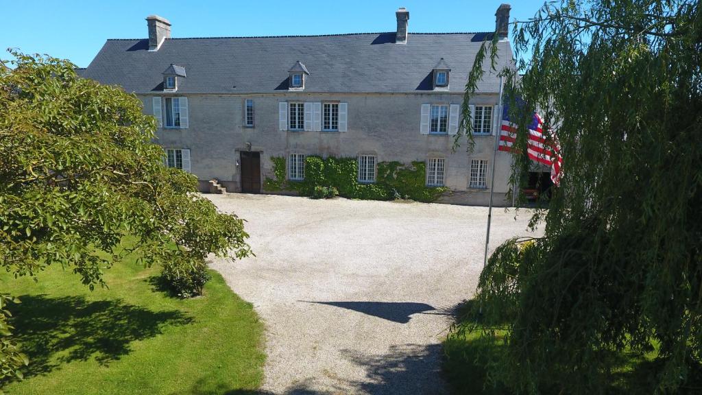 una casa grande con una bandera americana delante de ella en Sainte-Mère-Église - Ferme de Beauvais, en Sainte-Mère-Église
