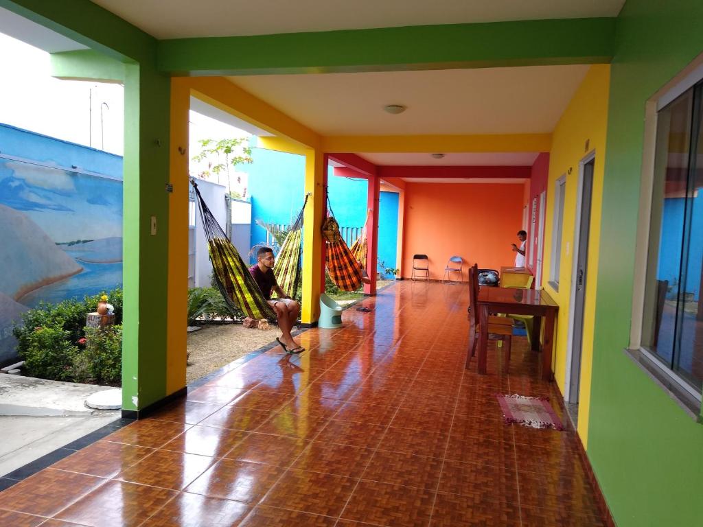 a man sitting on a hammock in the hallway of a house at Pousada Recanto Cruzeiro in Barreirinhas