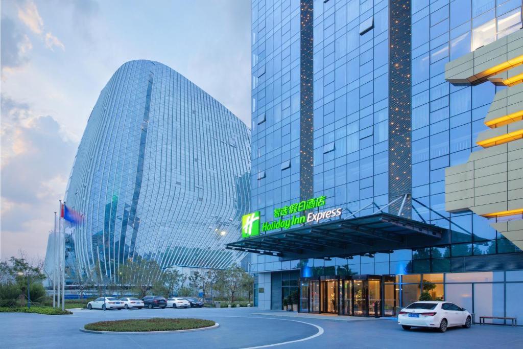 eine Gruppe von Gebäuden mit Autos auf einem Parkplatz in der Unterkunft Holiday Inn Express Zhengzhou Longzi Lake, an IHG Hotel in Yaoqiao