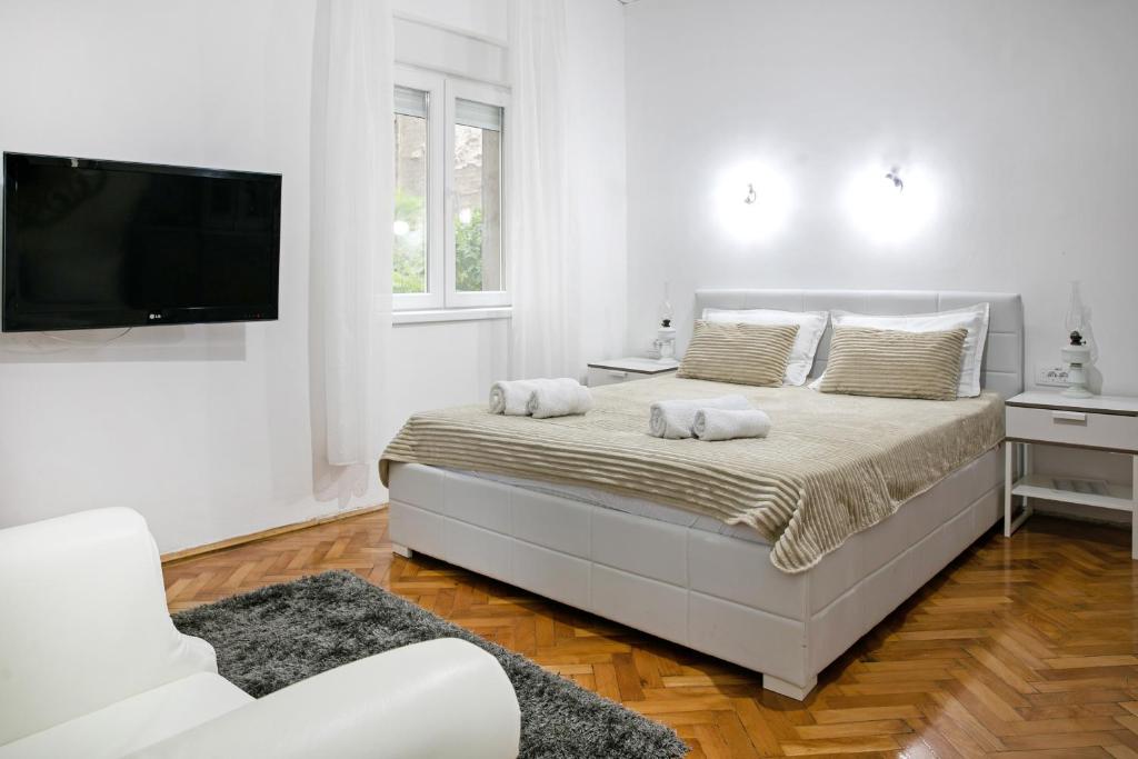 Un dormitorio blanco con una cama y un televisor de pantalla plana. en Natalie's Home, en Belgrado
