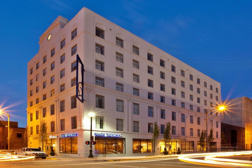 een groot wit gebouw in een stadsstraat 's nachts bij Hotel Indigo Baton Rouge Downtown, an IHG Hotel in Baton Rouge