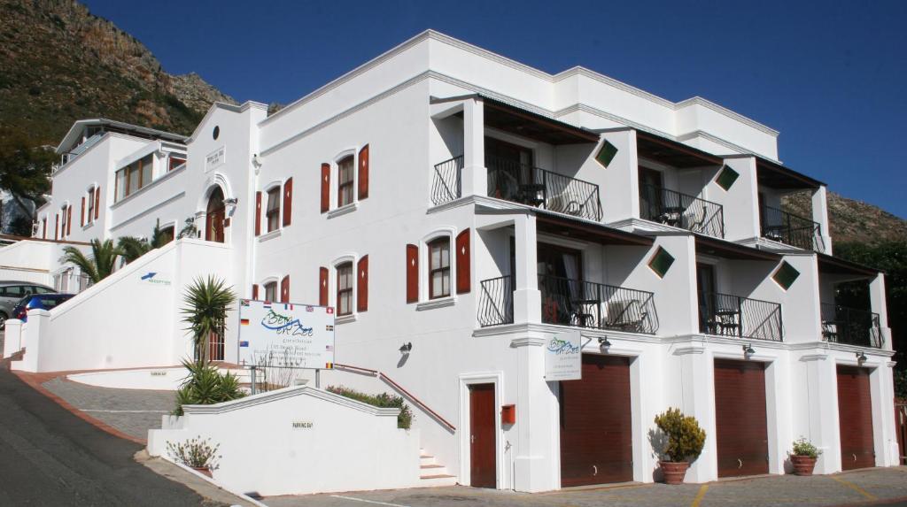 een wit gebouw met rode deuren en balkons bij Berg en Zee Guesthouse in Gordonsbaai