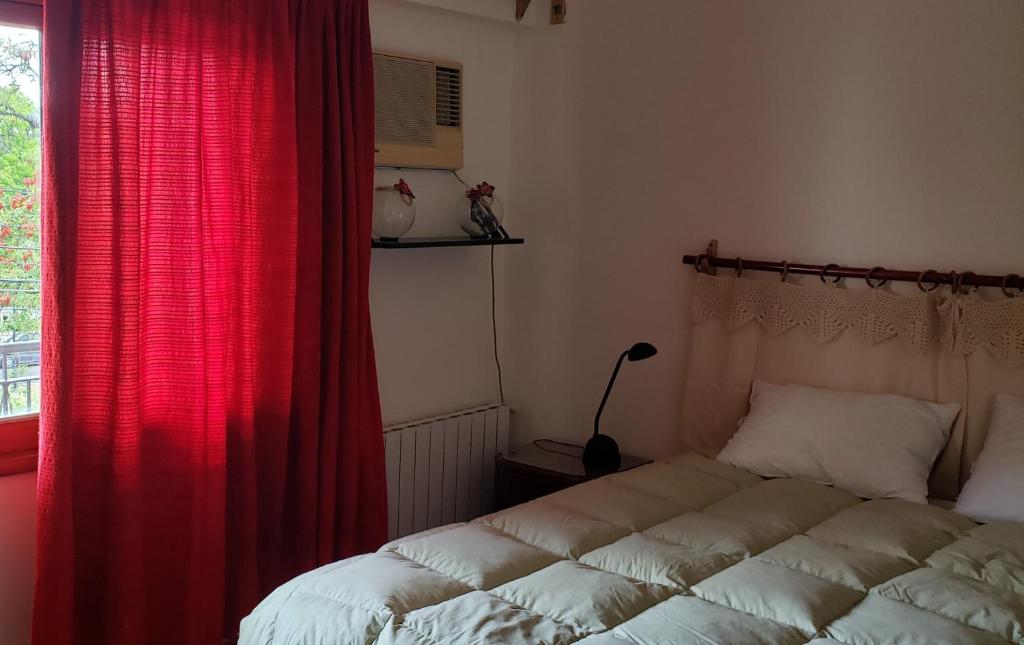 1 dormitorio con 1 cama con cortina roja y ventana en La casa del Paseo en Salta