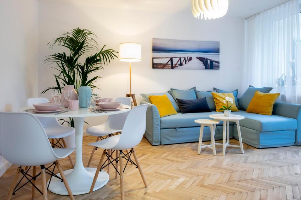 een woonkamer met een blauwe bank en een tafel en stoelen bij CRISTINE APARTMENT in Warschau