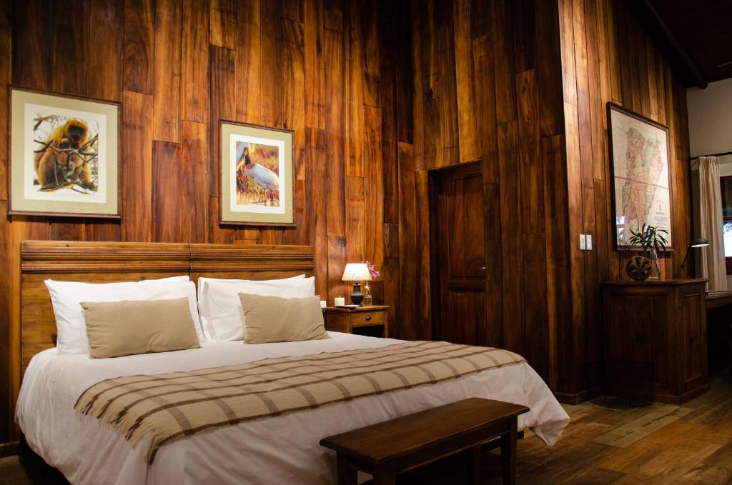 1 dormitorio con 1 cama grande y paredes de madera en El Tránsito Hotel Boutique en Concepción