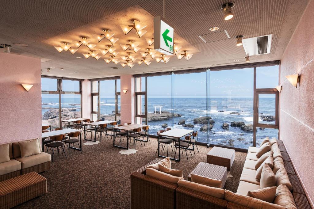 een restaurant met tafels en stoelen en uitzicht op de oceaan bij Oarai Hotel Annex Gyoraian in Oarai
