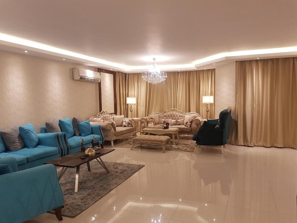 a large living room with blue couches and chairs at Lebanon Apartment in Cairo