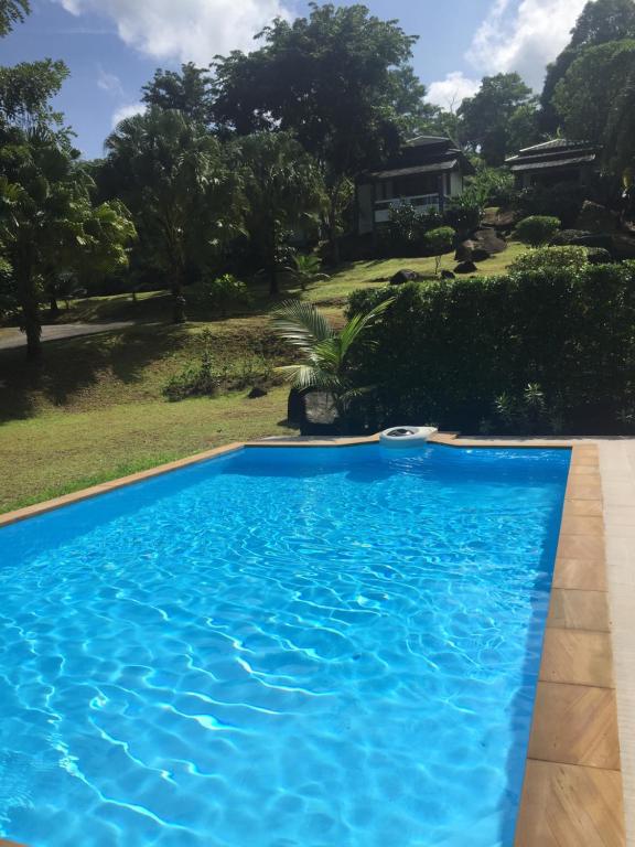 a blue swimming pool with a house in the background at Khaolak Hillside Villa in Khao Lak