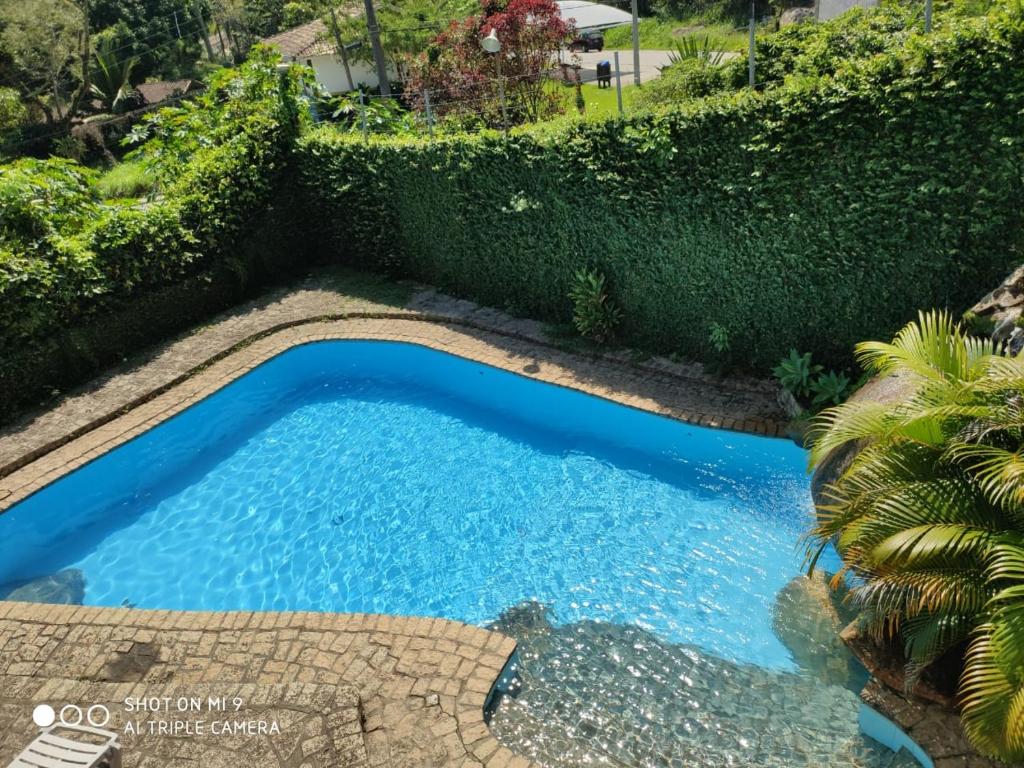 una piscina en un jardín con un seto en POUSADA TRUFFIMAR reservas Ilhabela en Ilhabela