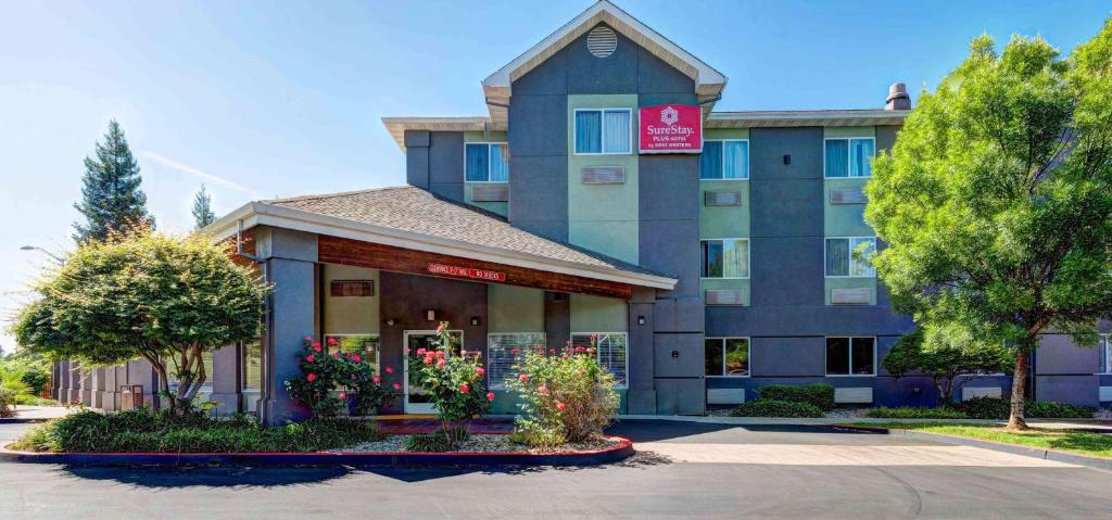 a hotel with flowers in front of a building at SureStay Plus Hotel by Best Western Redding in Redding