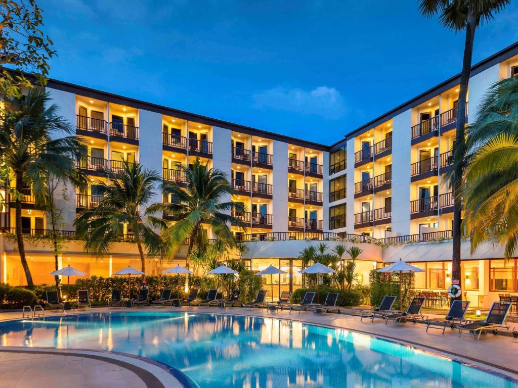 a hotel with a swimming pool in front of a building at Ibis Phuket Patong in Patong Beach