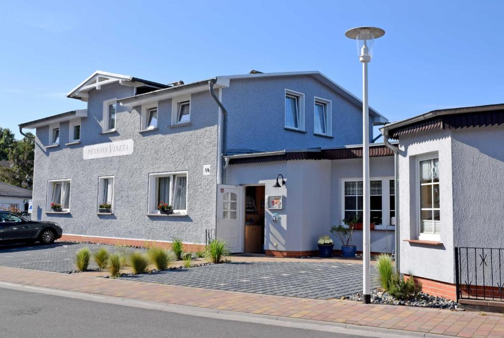 un bâtiment bleu et blanc avec un parking dans l'établissement Pension Vineta Ostseebad Baabe, à Baabe