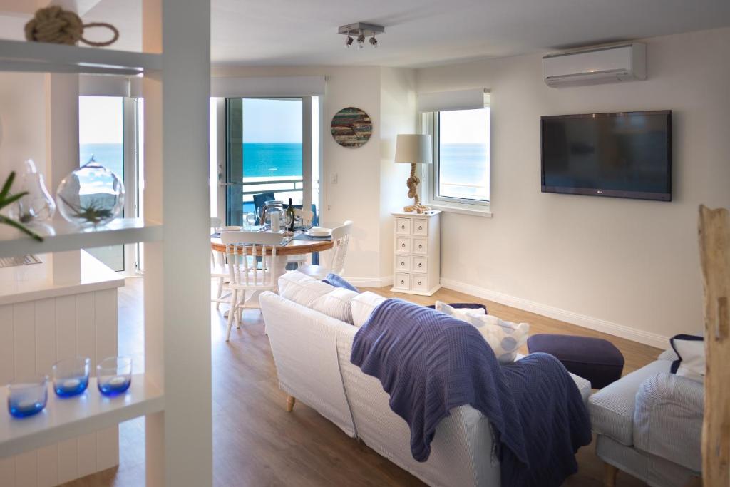 een woonkamer met een witte bank en een tafel bij Cottesloe Blue Apartment in Perth