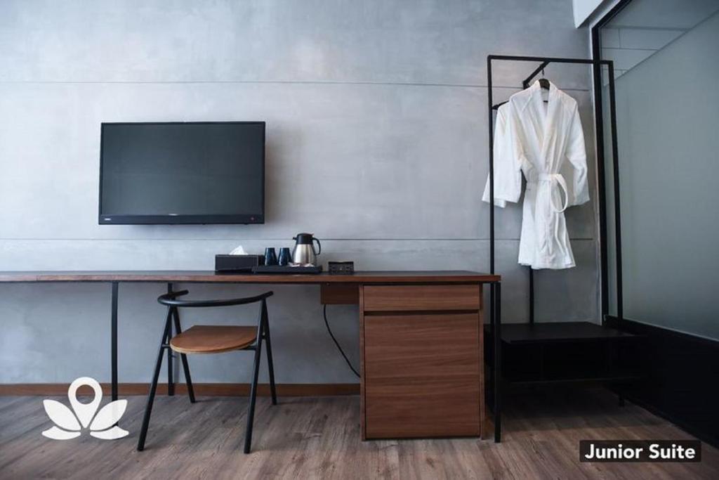 A full-width desk with television, chair, kettle and hanging bathrobe in a Junior Suite.