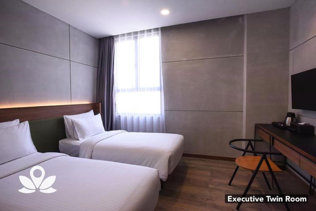 A twin room with two separate beds, a curtained window and a compact television desk.