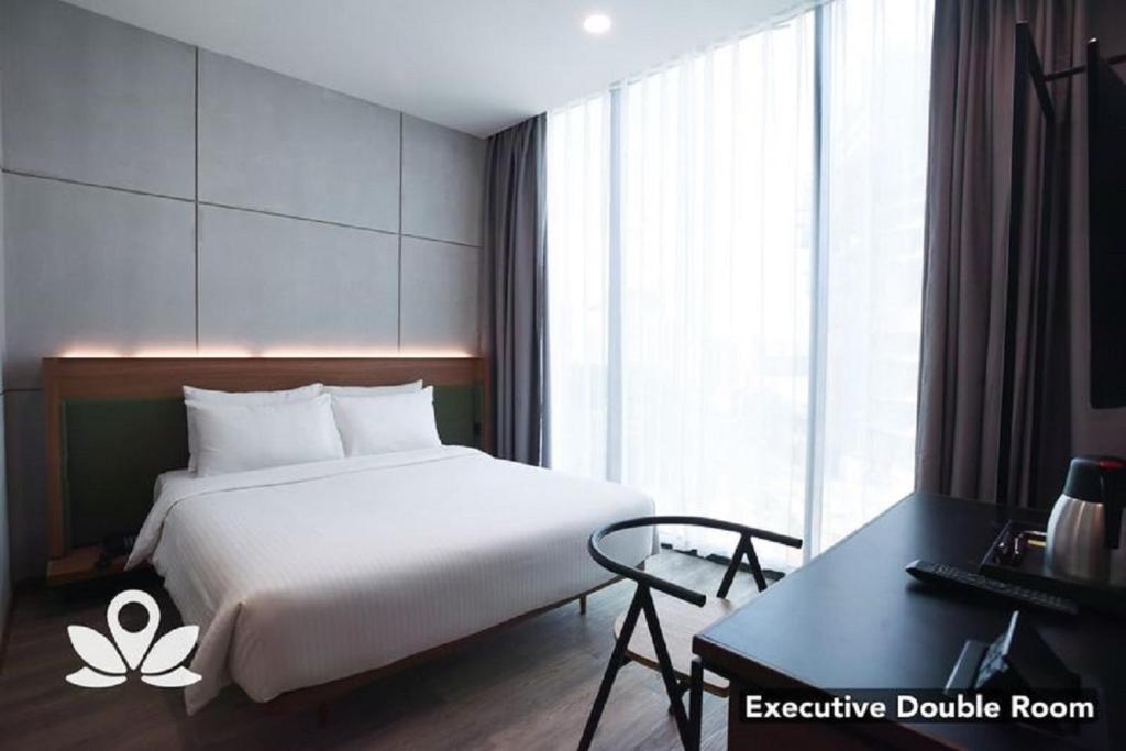 um quarto com uma cama branca e uma secretária em Ceria Hotel em Kuala Lumpur