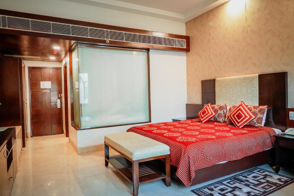 a bedroom with a red bed and a large window at Hotel Airport Residency in New Delhi