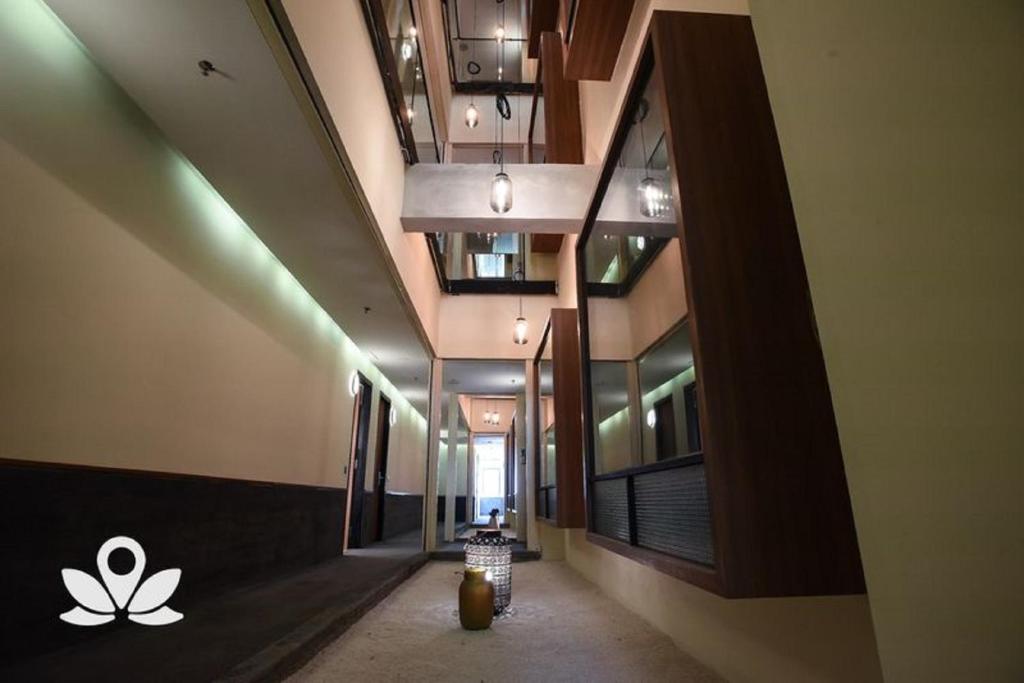 A long interior corridor with glass-fronted atrium openings, pendant lights and decorative seating.