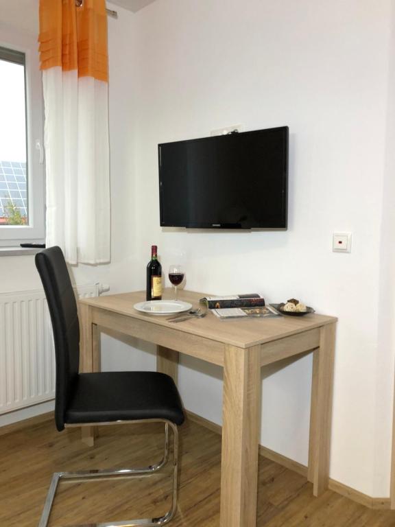 a desk with a chair and a television on a wall at zollwanger - Wohnen auf Zeit in Dillingen an der Donau
