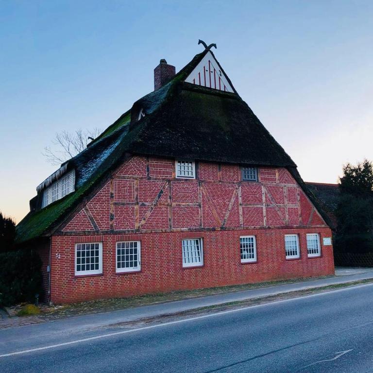 a red barn with a grass roof on a street at Ferienwohnung Mila in Grevenkop