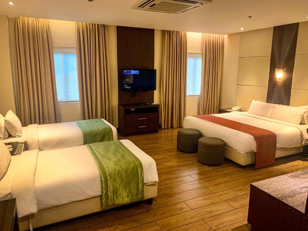 Habitación de hotel con 2 camas y TV de pantalla plana. en Hotel Monticello Tagaytay en Tagaytay