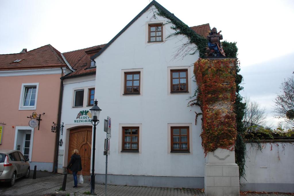 Ein weißes Haus mit einer Statue auf der Seite. in der Unterkunft Gasthof Ludl in Groß-Enzersdorf