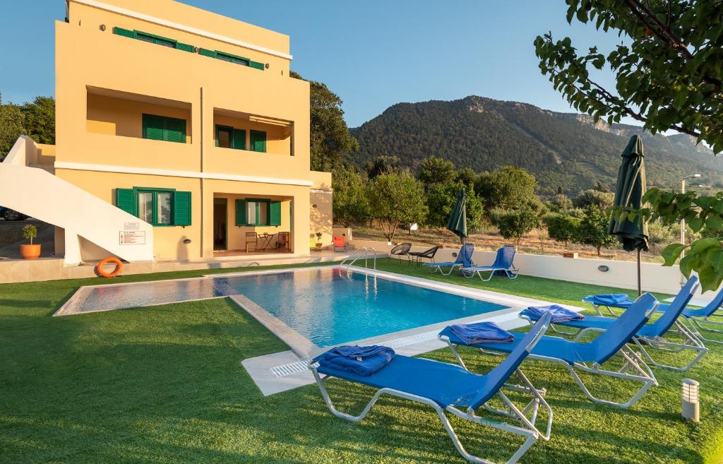 a villa with a swimming pool and two lawn chairs at Anemos Villa in Sálakos