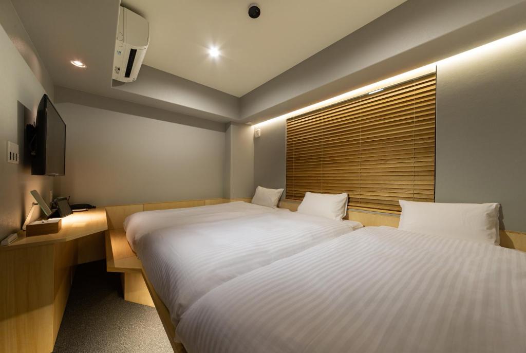 Rúm í herbergi á HOTEL AMANEK Kyoto Kawaramachi Gojo