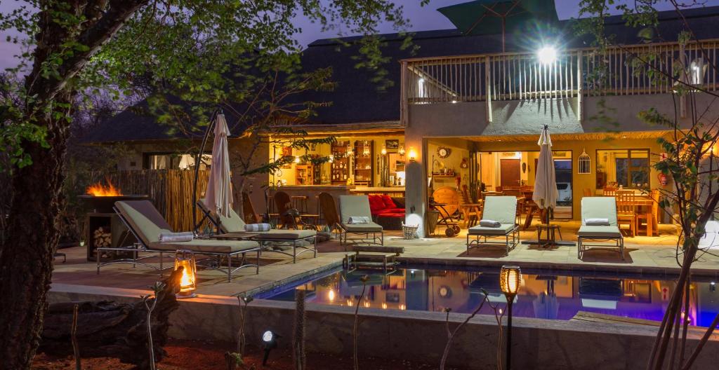 a backyard with a pool and chairs and a house at Ukuthula Bush Lodge in Hoedspruit