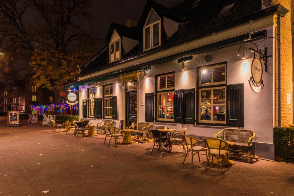 un groupe de tables et de chaises à l'extérieur d'un bâtiment dans l'établissement Hotel Het Witte Paard, à Etten-Leur