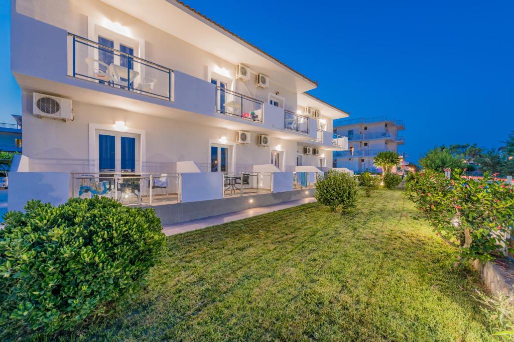 un gran edificio blanco con un patio delante en Stathis Studios II with Sea View en Laganas