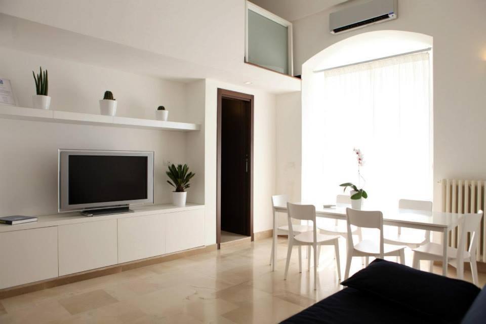 ein Wohnzimmer mit einem TV und einem Tisch mit Stühlen in der Unterkunft B&B Al Duomo Molfetta in Molfetta