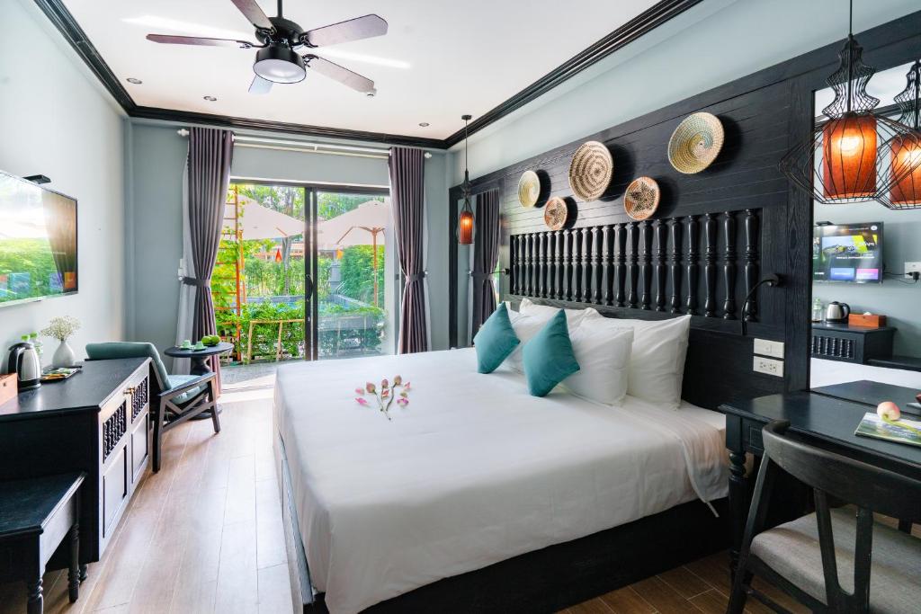 ein Schlafzimmer mit einem großen Bett, einem Schreibtisch und einem Tisch in der Unterkunft Daisy An Bang Villa in Hoi An