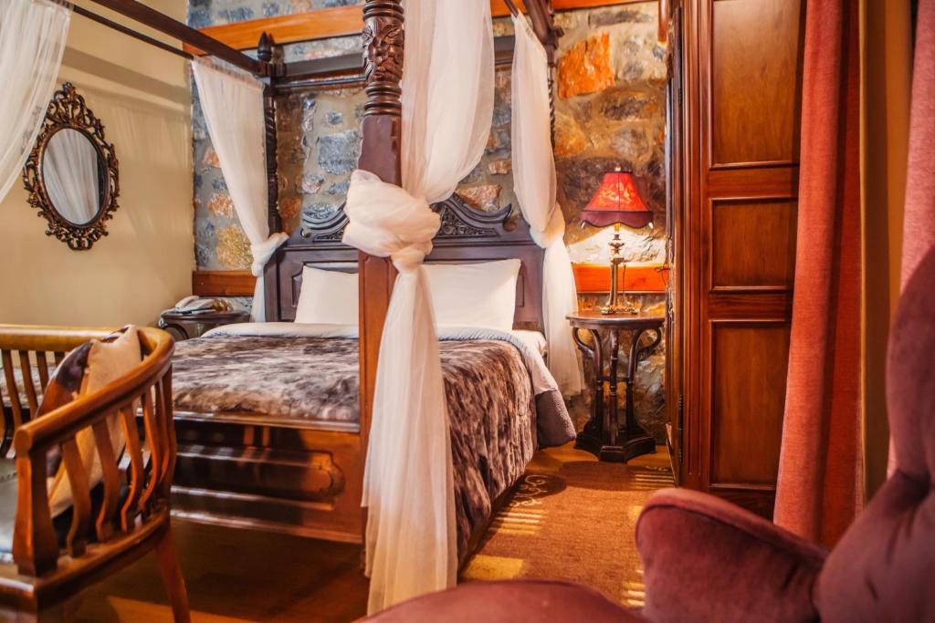 パライオス・アギオス・アタナシオスにあるMontecristo Chaletのベッドルーム(天蓋付きベッド1台、椅子付)