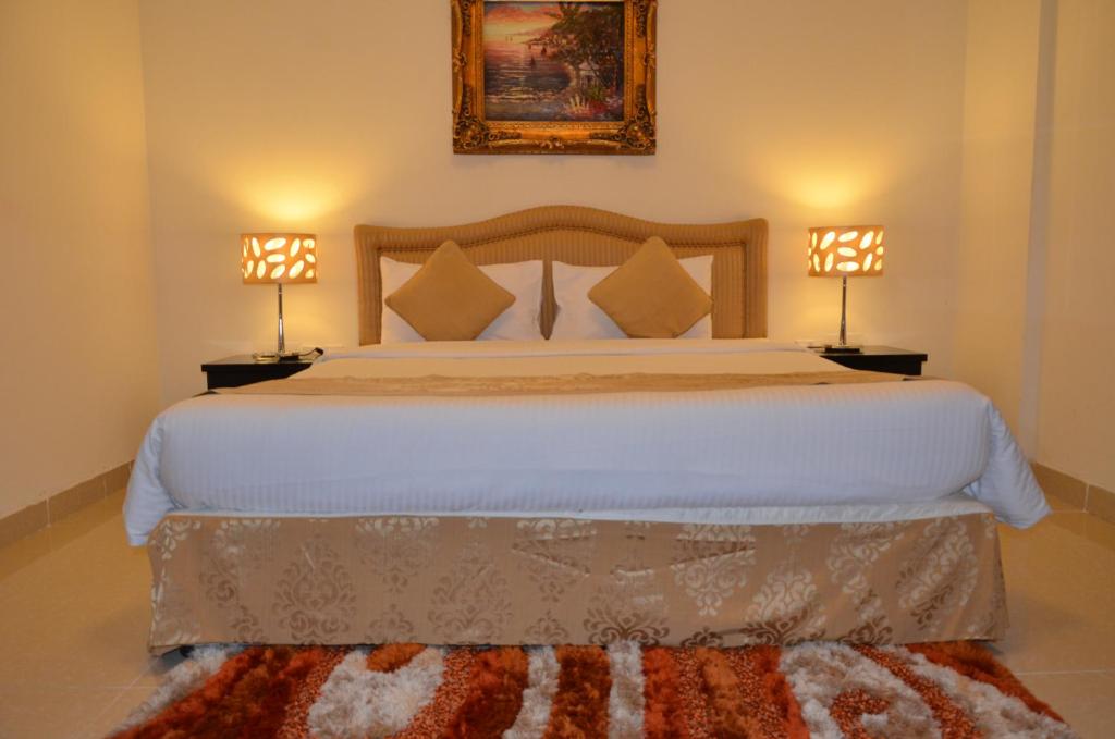 a bedroom with a large white bed with two lamps at Al Jazeera Hotel Apartments LLC in Dubai