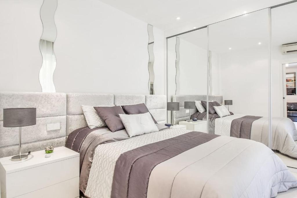 a white bedroom with two beds and mirrors at Charming 1BR Apartment In Heart Of Monaco in Monte Carlo