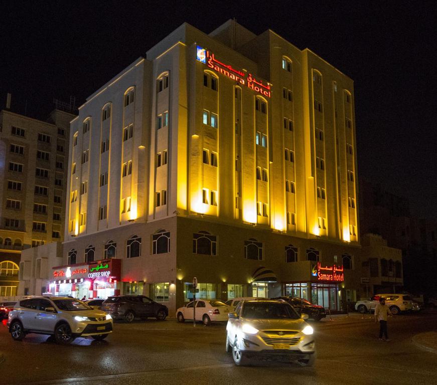 a yellow building with cars parked in front of it at Samara Hotel in Muscat