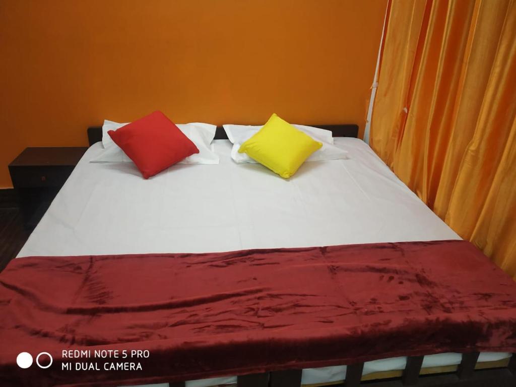 a bed with three colorful pillows on it at The coloursinn Home stays in Chennai