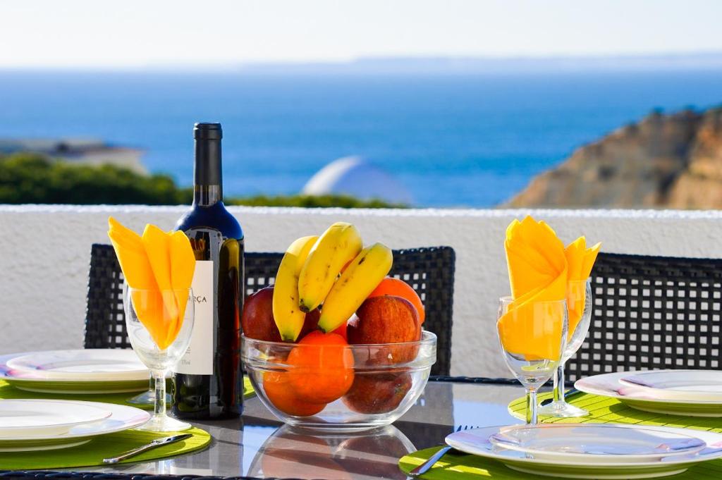 uma mesa com uma garrafa de vinho e uma taça de fruta em Algarpraia em Carvoeiro