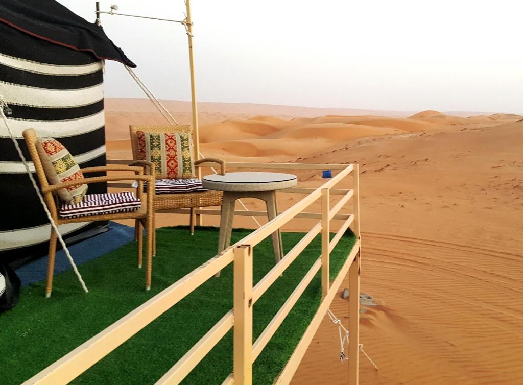 a table and two chairs in the desert at Hamood desert local camp in Al Wāşil