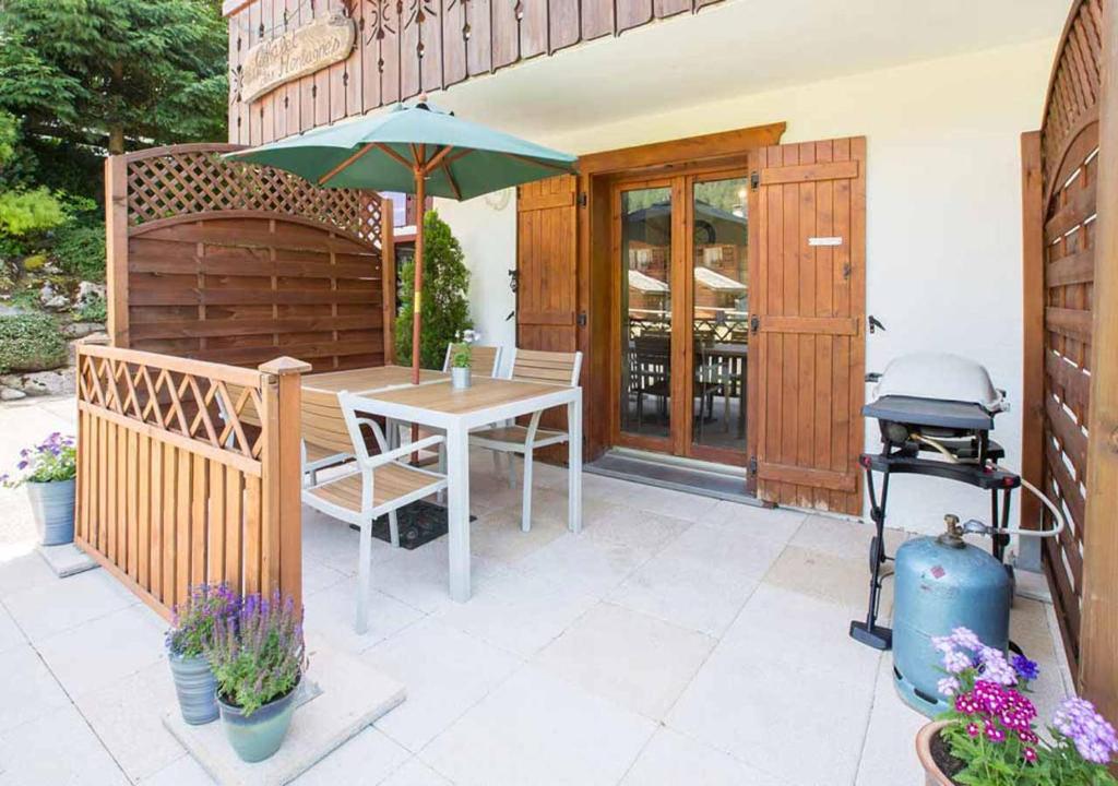 d'une terrasse avec une table et un parasol vert. dans l'établissement Simply Morzine - Apartment des Montagnes, à Morzine